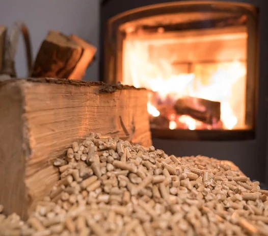 Bûches et granulés devant un poêle allumé à Lalinde